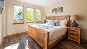 A bedroom with a wooden bed, two bedside tables, and a wall-mounted lamp.