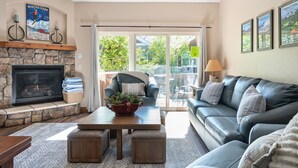 A cozy living room with a stone fireplace, a leather sofa, and a dining table.