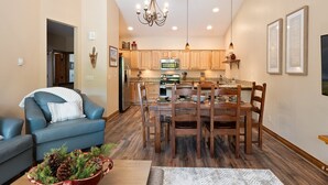A modern kitchen with wooden cabinets, a dining table, and a chandelier.