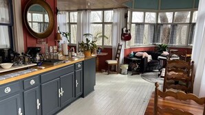 A cozy kitchen with a central island, wooden cabinets, and a large window with curtains.