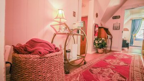 A cozy room with a red carpet, a wicker chair, a lamp, and a mirror.
