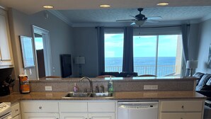 A kitchen with white cabinets, a dishwasher, and a view of the ocean. - Best View On The Beach.  Complimentary beach service. (Panama City Beach)