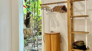 Ein Zimmer mit Holzboden, einer Bambustrommel, einem Holzleiterregal und einer Tür zu einem Garten.