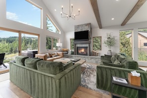 A spacious living room with a fireplace, large windows, and a view of the outdoors.