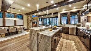 Una cocina moderna con una isla grande, electrodomésticos integrados y una chimenea de piedra.