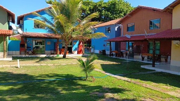 A courtyard with a palm tree, outdoor seating, and a building with a red roof.
