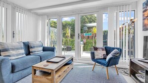 A modern living room with a blue sofa, a wooden coffee table, and a blue armchair. - Garden Room With Parking By My Getaways (Lancing)