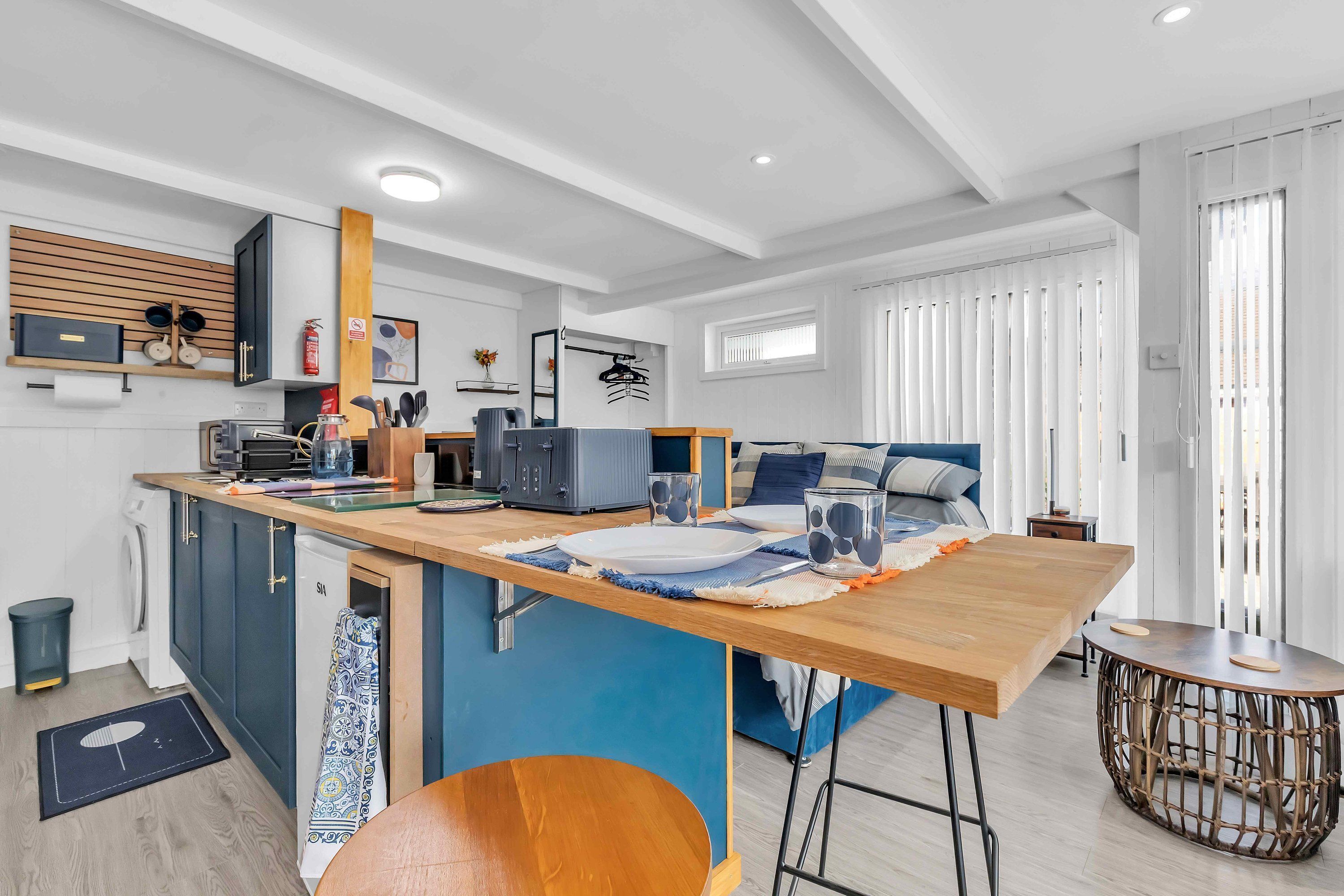 A modern kitchen with a wooden island, built-in appliances, and a blue accent wall.