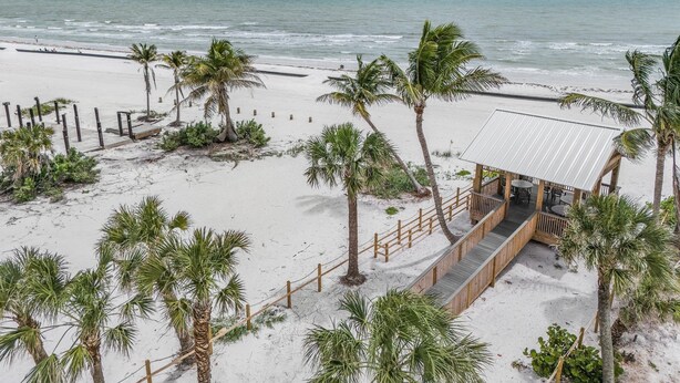 A beachside property with a wooden deck, palm trees, and a small building with a metal roof.