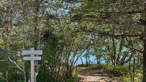 Un chemin de terre mène à une plage, et un panneau indique qu’elle est accessible au public, mais qu’il est interdit de s’y garer.