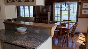 Une cuisine dotée d’un plan de travail en granit, d’un lave-vaisselle et d’un coin repas avec des chaises et une table en bois.