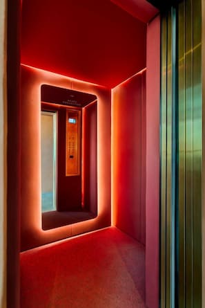 A modern elevator with a digital display, surrounded by red walls and a carpeted floor. - Brada Collection Stays (Guadalajara)