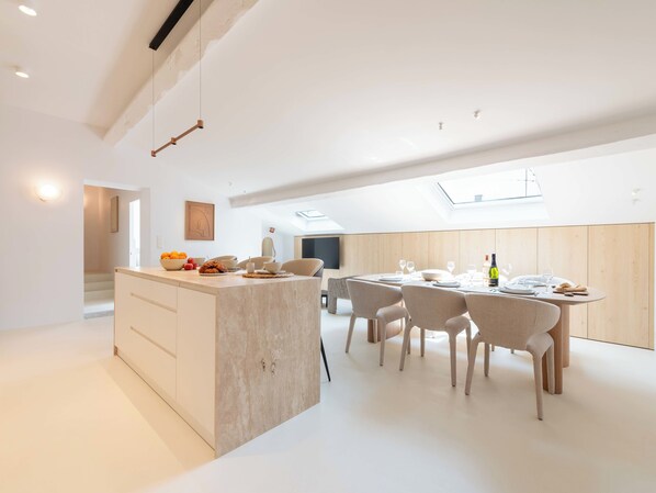 A modern kitchen with a central island, dining area with chairs, and a large window. - 3-Br Attic Duplex – Heart of Cannes (Cannes)