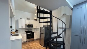 A modern kitchen with white cabinets, stainless steel appliances, and a wooden floor.