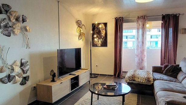 Un salon équipé d’un téléviseur à écran plat, d’un ventilateur de plafond, d’un canapé et d’une table basse.