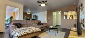 Ein Wohnzimmer mit Sofa, Couchtisch, Fernseher und Deckenventilator.