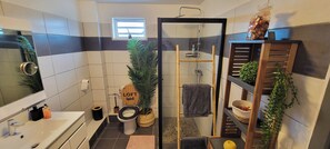 Ein Badezimmer mit einem weißen Waschbecken, einer Toilette mit dem Schild 'LOFT Spirit' sowie einer Duschkabine und einem kleinen Fenster.