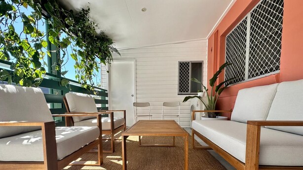 Un patio iluminado por el sol con una mesa de madera, dos sofás y sillones.