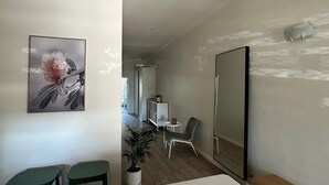 Una habitación moderna y minimalista con un espejo grande, una mesa de comedor y dos sillas verdes.