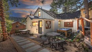 Een chalet met een terras, een tafel en lichtslingers.