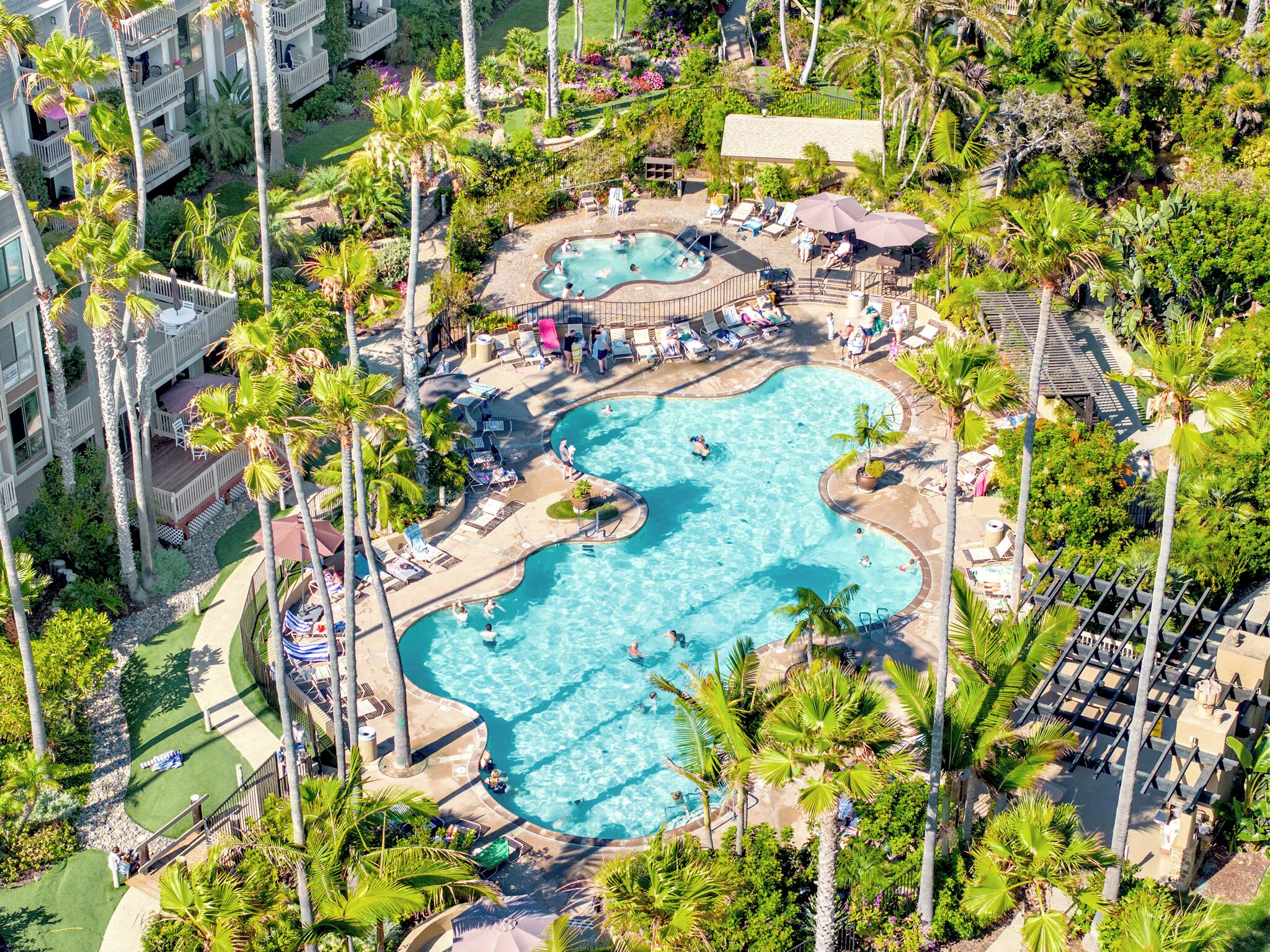 Een resort met een groot centraal zwembad, meerdere kleinere zwembaden en talloze palmbomen.