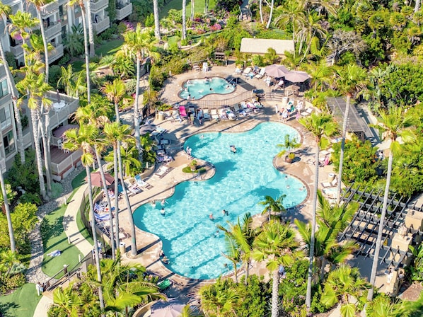 A resort with a large central pool, multiple smaller pools, and numerous palm trees.