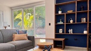Un salon moderne avec un canapé gris, une table basse en bois et une bibliothèque bleue.