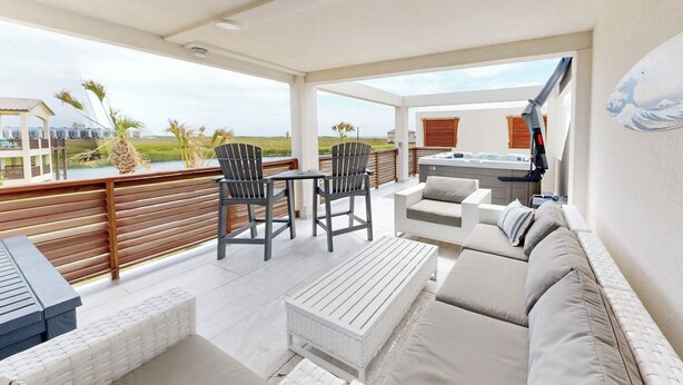A covered outdoor patio with a hot tub, seating area, and a view of the beach. - Beach Access, Private Hot Tub, Shared Pool (Port Aransas)