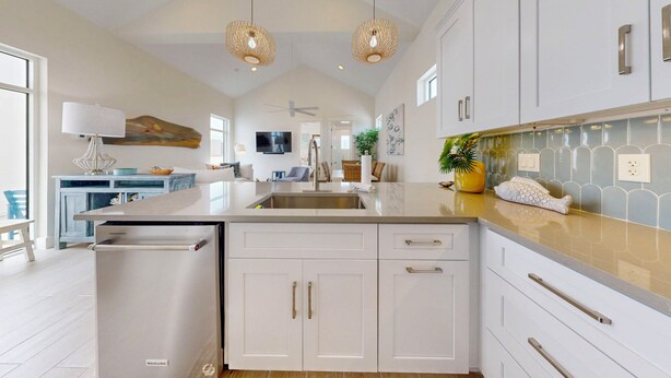 A modern kitchen with white cabinetry, a large island, and pendant lighting. - Beach Access, Private Hot Tub, Pet Friendly, Shared Pool (Port Aransas)
