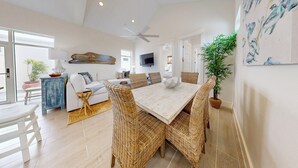 A spacious living area with a dining table, wicker chairs, a sofa, and a ceiling fan. - Beach Access, Private Hot Tub, Pet Friendly, Shared Pool (Port Aransas)
