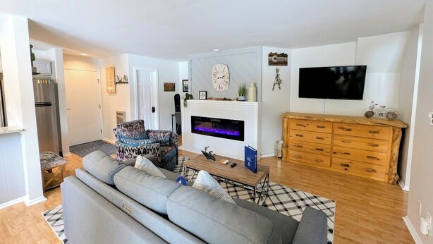 A modern living room with a grey sofa, a fireplace, a TV, and a wooden cabinet. - Flying Dutchman 1155 (Keystone)