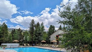 A swimming pool with lounge chairs and umbrellas, surrounded by trees and a building. - Flying Dutchman 1155 (Keystone)