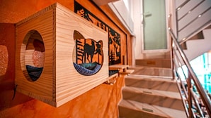 Una struttura in legno con decorazioni intagliate, forse un elemento decorativo o un mobile, in un ambiente interno moderno con una scala.