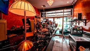A bar area with a lamp, shelves with bottles, and a view of the street outside. - DANK HOTEL 420 Friendly (Patong)