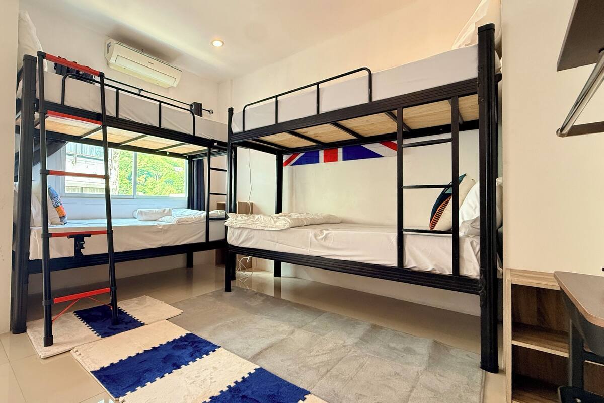 A room with bunk beds, a window with a view, and a small desk.