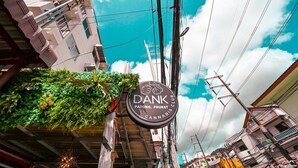 Segnaletica per 'Dank Patong, Phuket Cannabis Club' con vista su un edificio e linee elettriche.