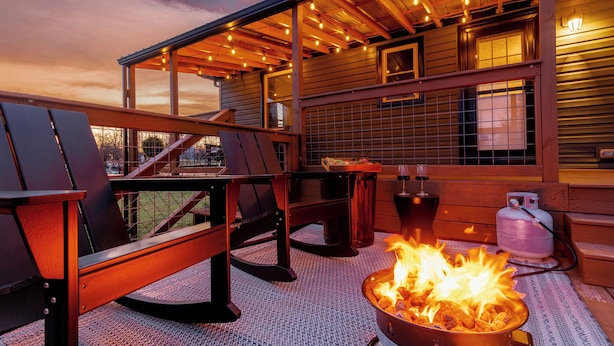 An outdoor patio with a fire pit, wooden chairs, and a table.