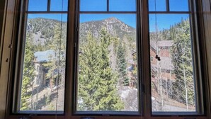 A room with a large window offering a view of a mountainous landscape with trees and buildings. - Settlers Creek 6521 (Keystone)