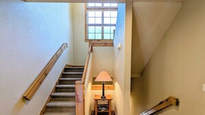 A staircase with wooden handrails, carpeted steps, and a small table with a lamp at the bottom. - Settlers Creek 6521 (Keystone)