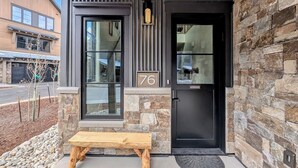 A modern building with a stone facade, a black door, and a bench outside.