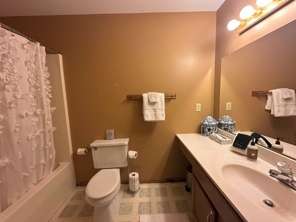 Een badkamer met toilet, wastafel en douchegordijn.