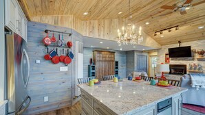 A kitchen with wooden paneling, a large island, and a chandelier. - River Place Retreat- Perfect Retreat for Large Groups or Families (Howard)