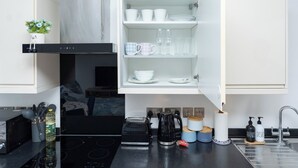 Une cuisine moderne avec des meubles blancs, un four encastré et une machine à café.