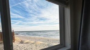A room with a window overlooking a sandy beach and the ocean. - Oceanfront Ground Floor End-Unit Condo w/pool -
Shamrock Sands M1 @ The Riggings (Kure Beach)