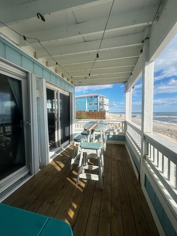 A wooden deck with a view of a beach and a multi-story building.