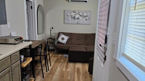A compact living space with a kitchenette, a sofa, and a ceiling fan. - Clinton Cabins #2 (Clinton)