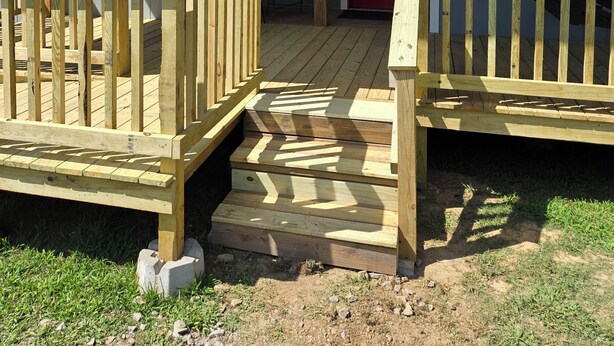 A wooden deck with a red door and a covered porch area. - Clinton Cabins #2 (Clinton)