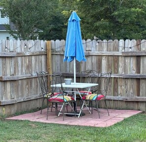 Une terrasse avec une table et des chaises, un parasol bleu et une clôture en bois en arrière-plan.