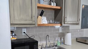 A kitchen with wooden cabinets, a stainless steel sink, a microwave, and a clock on the wall. - Clinton Cabins #2 (Clinton)