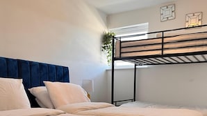 A bedroom with a bunk bed and a double bed, both with white bedding.
